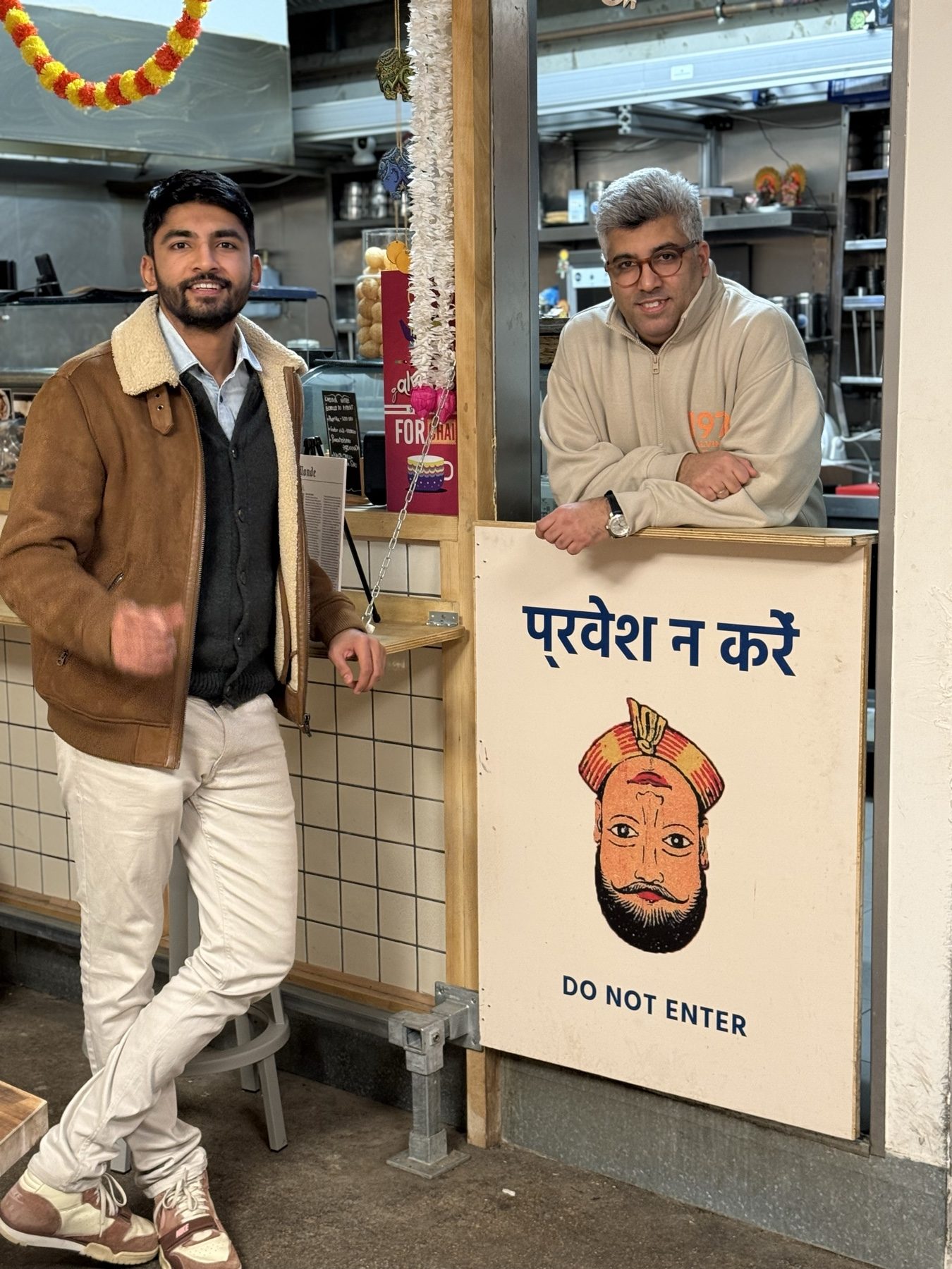 Manan Mehta standing with a restaurant owner at the counter of his kitchen in Paris