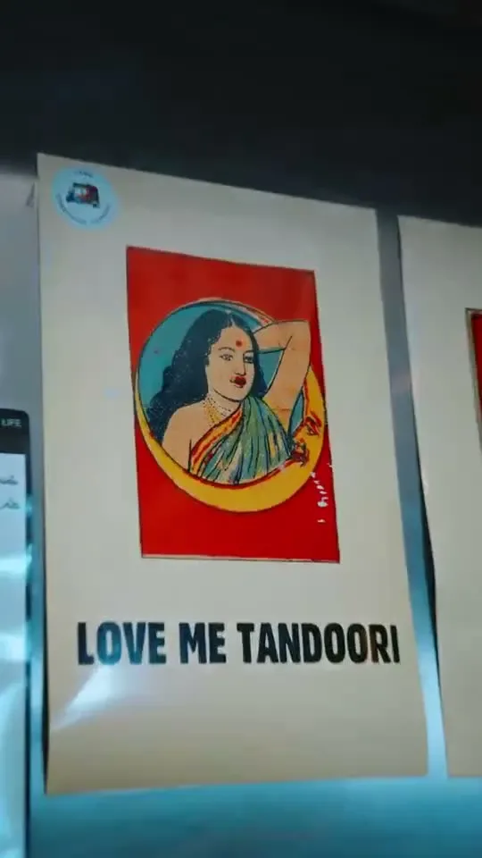 A framed poster on a wall reading Love Me Tandoori