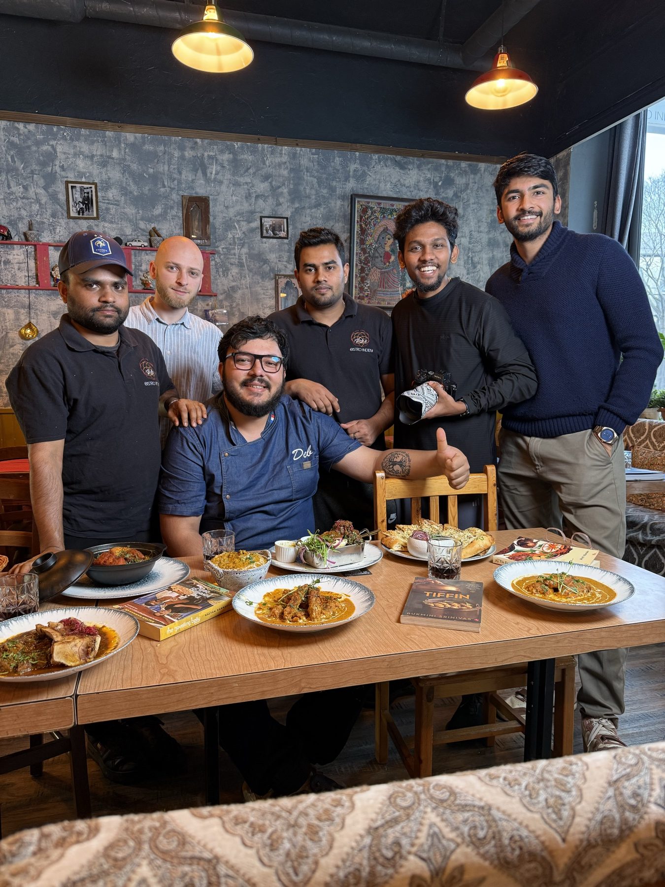 Six people around a restaurant table in Lyon with plates of Indian food in front of them