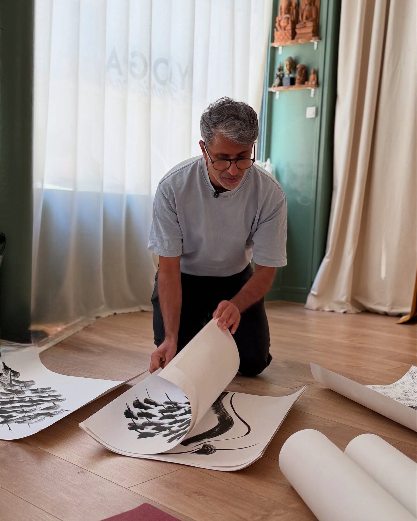 A business owner laying out printed artwork on the floor of his shop