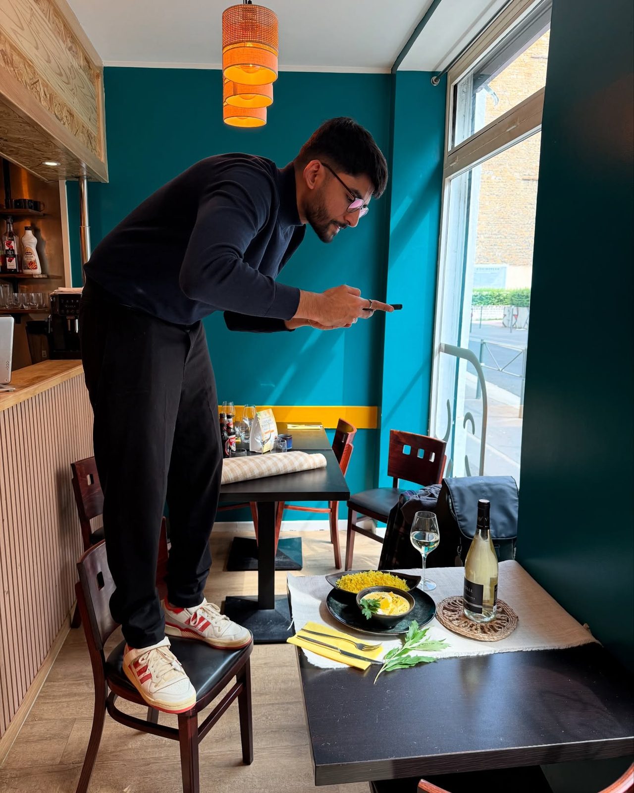 Manan Mehta standing on a chair to photograph a plated dish in a restaurant