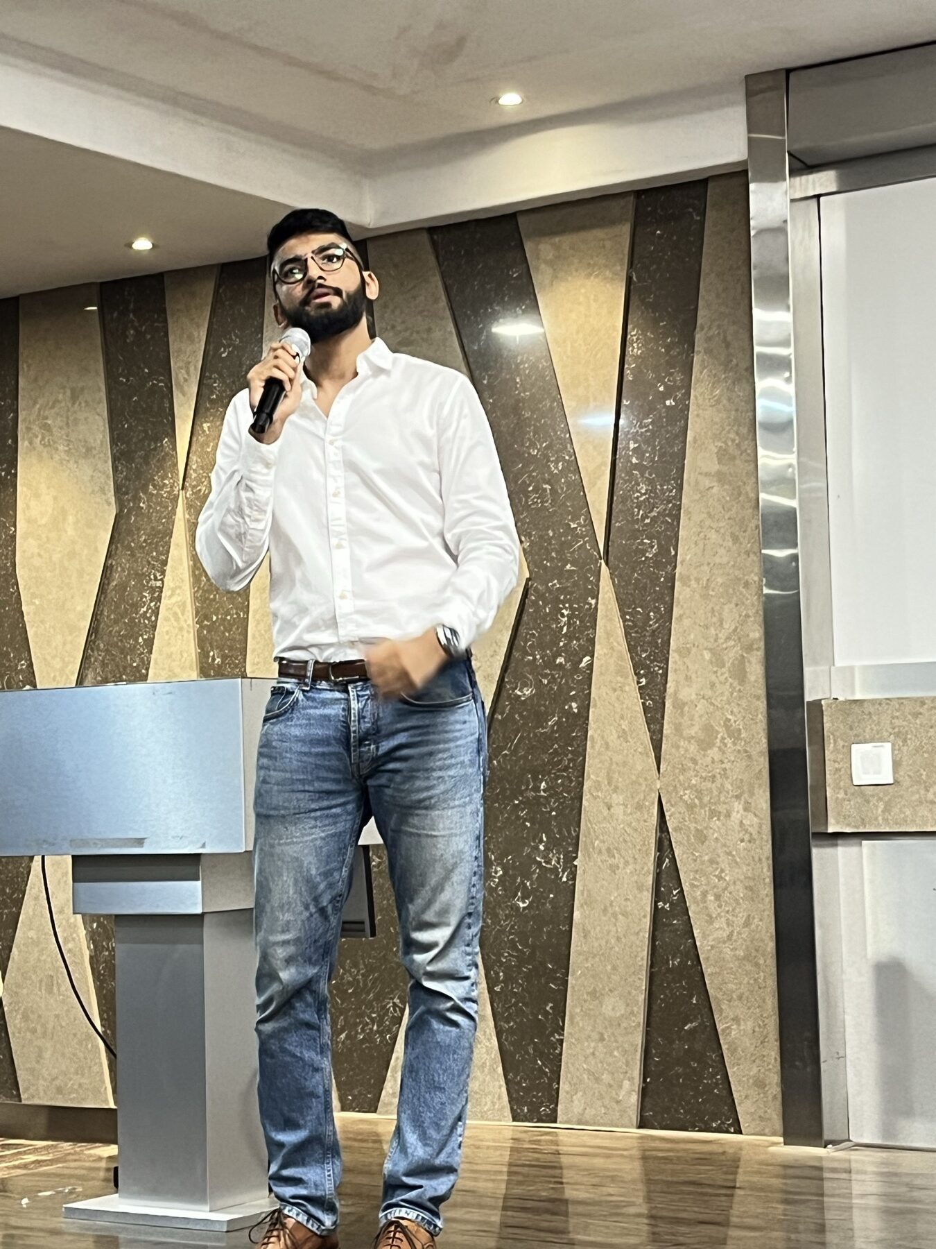 Manan Mehta speaking with a microphone on stage at a marketing event