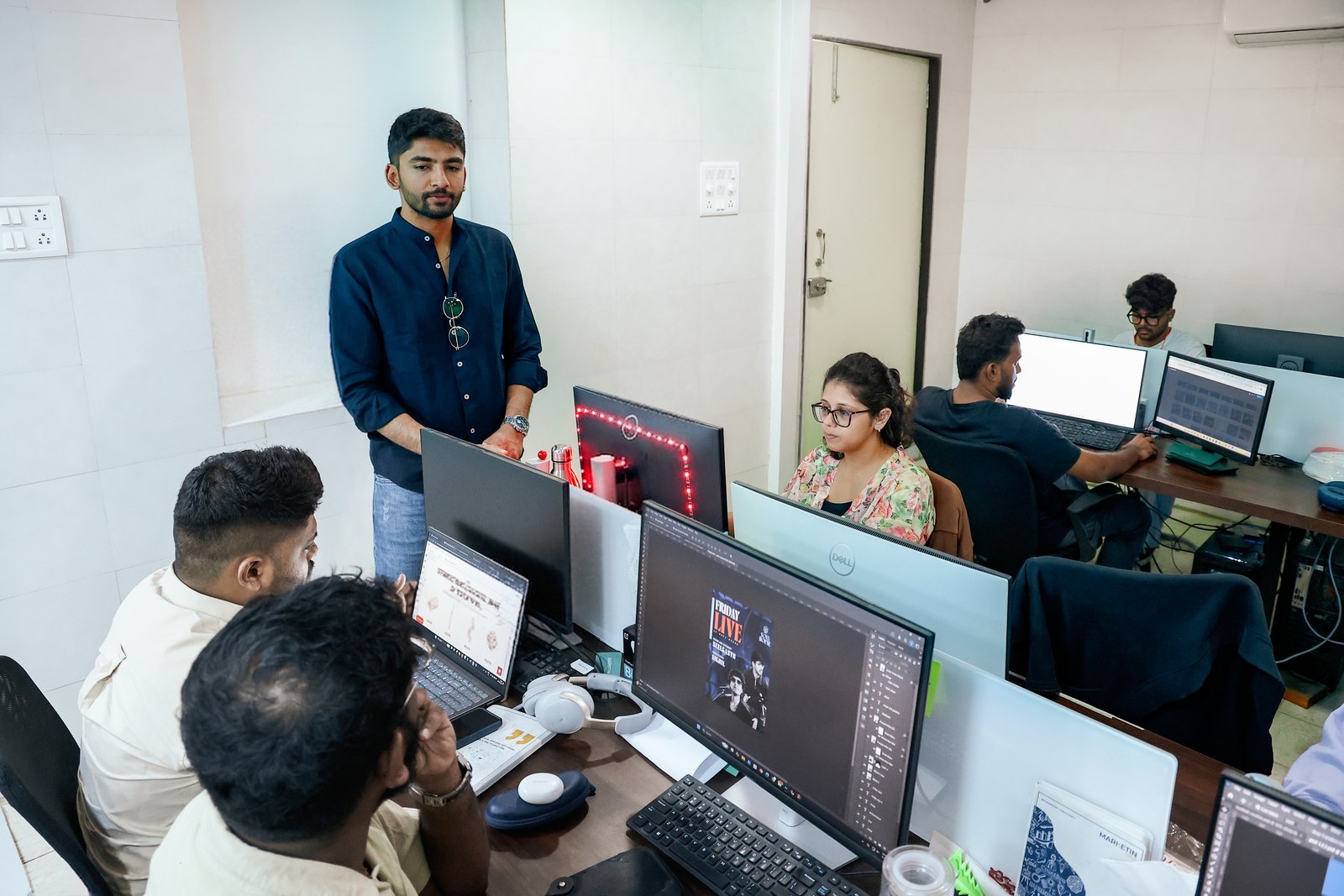 Manan Mehta standing with the team at their monitors in the Mumbai office