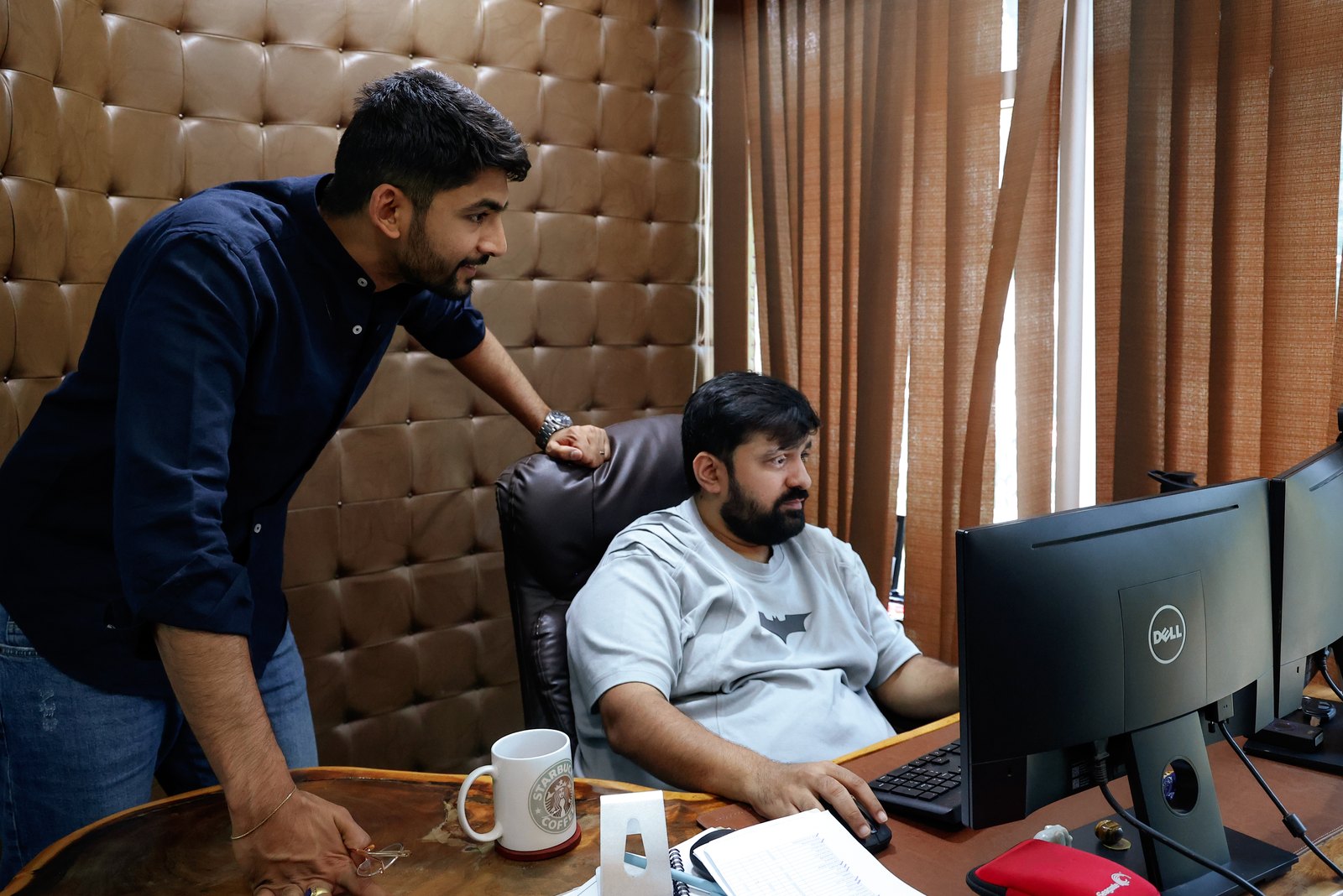 Manan Mehta going through the numbers on screen with a colleague at their desk